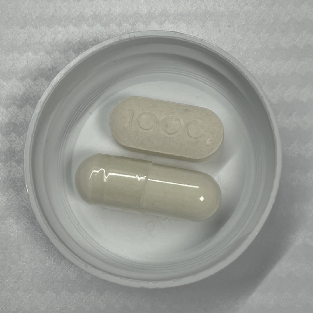 Jarrow mastic gum capsule next to a 1000mg vitamin C tablet for size comparison